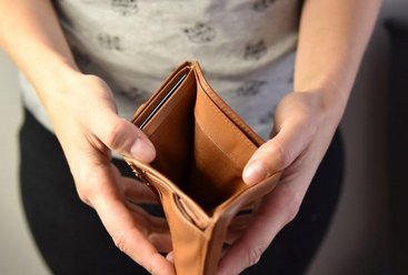 Eine Frau Im mittleren Alter öffnet ein Portemonnaie ohne Geld drin