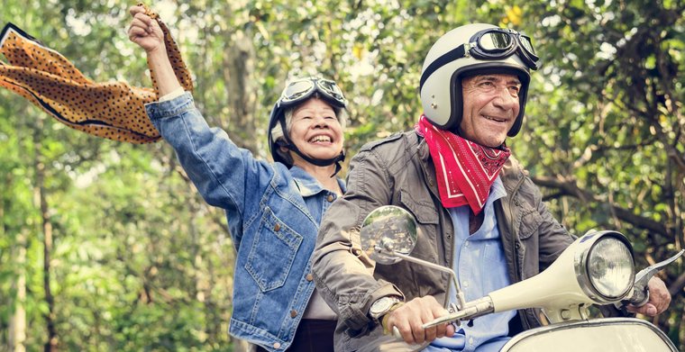 Photo d’un homme âgé sur une moto. Derrière lui, sur la moto, une femme souriante d’un certain âge.