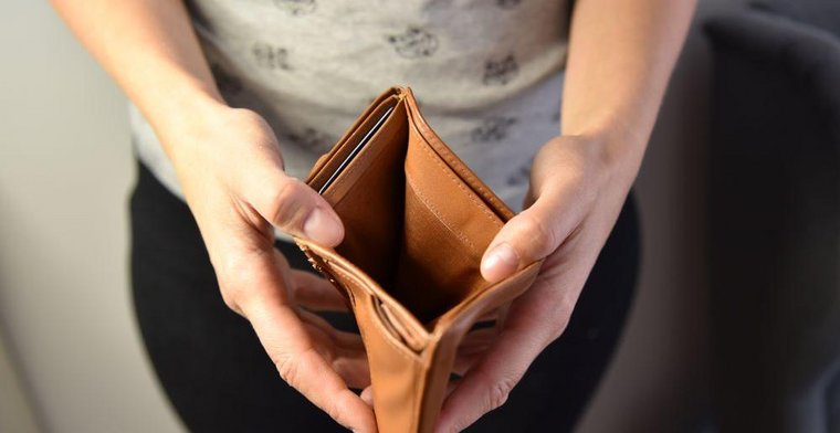 Une femme d'âge moyen ouvre un porte-monnaie sans argent à l'intérieur